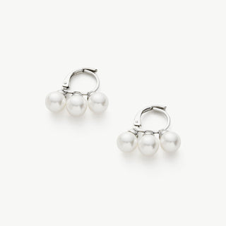 Pearl Huggies in Silver, a graceful and enchanting pair of huggie earrings featuring lustrous pearls embraced by a cool and silver setting